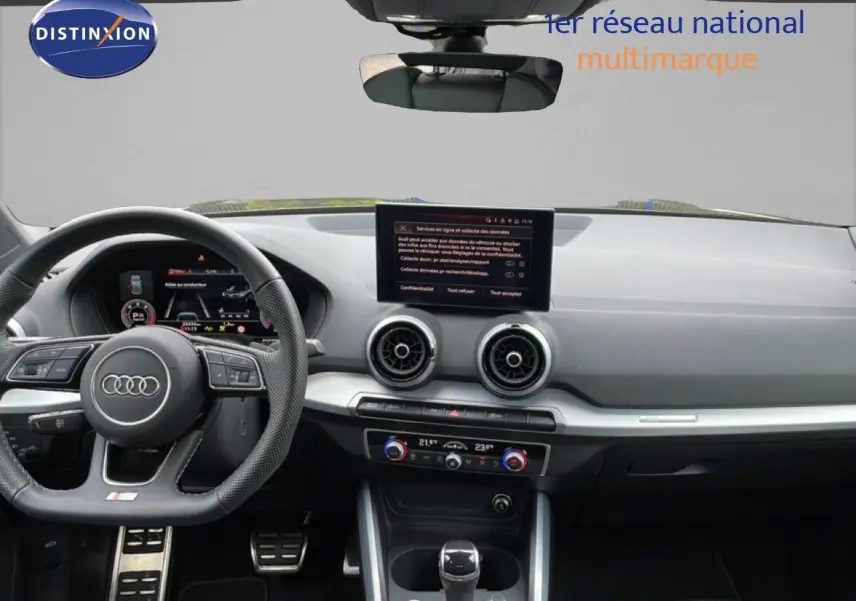 Vue intérieure de l'Audi Q2 S-Line 2025, tableau de bord noir avec volant sport et écran central tactile.