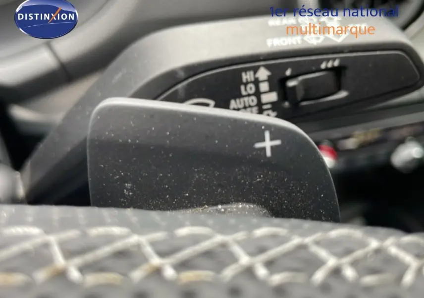 Gros plan sur la palette de changement de vitesse + du volant cuir noir de l'Audi Q2 2025 en intérieur.