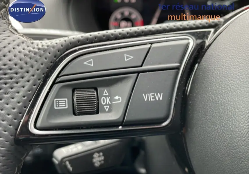 Gros plan sur les commandes multifonctions noires du volant perforé de l'Audi Q2 2025, finition S-Line.