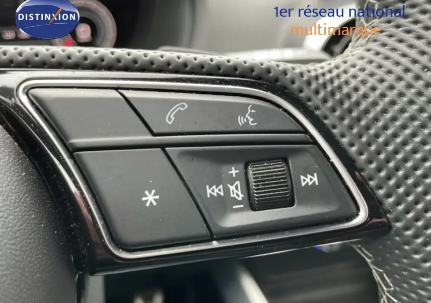 Gros plan sur les commandes multifonctions en cuir perforé du volant de l'Audi Q2 noir mito metal, côté gauche.