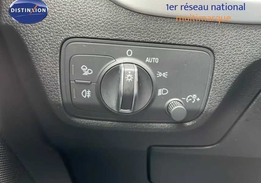 Gros plan sur le bouton de commande des phares de l’Audi Q2 noir mito metal, intérieur avec surface texturée noire.