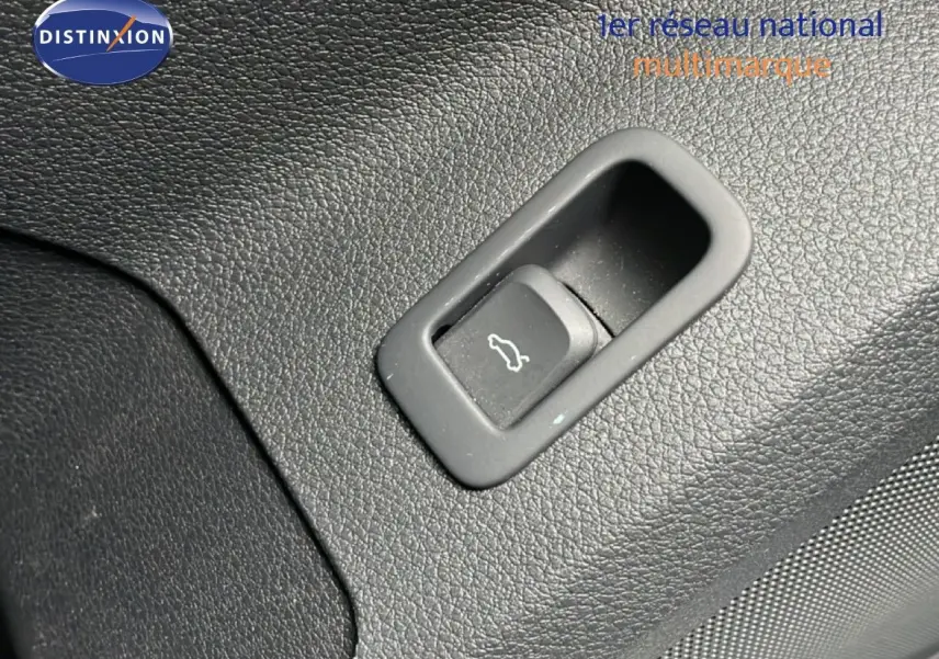 Gros plan sur le bouton d'ouverture de coffre intégré dans le revêtement noir texturé intérieur de l'Audi Q2 2025.