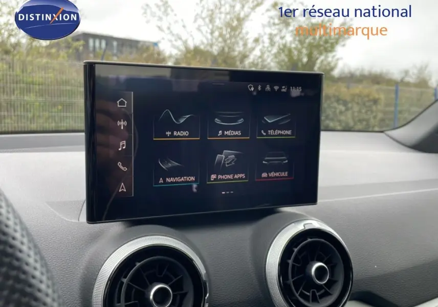Écran tactile central de l’Audi Q2 35 2.0 TDI S-Line 2025, intérieur noir avec aérateurs ronds argentés.