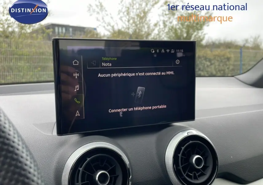 Écran tactile central et aérateurs ronds dans l’habitacle d’un Audi Q2 noir mito metal, vue intérieure avant.