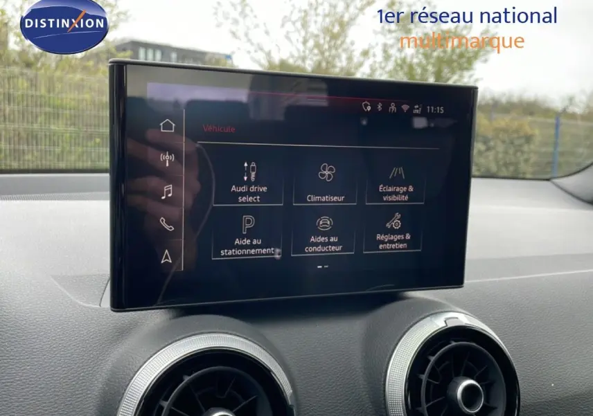 Vue intérieure de l'Audi Q2 2025, écran central tactile avec menu des aides à la conduite et climatisation.