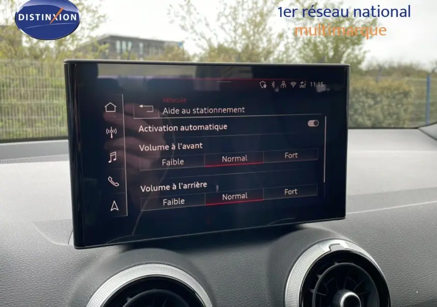 Écran central de l’Audi Q2 noir mito metal 2025 affichant les réglages d’aide au stationnement et volume sonore.