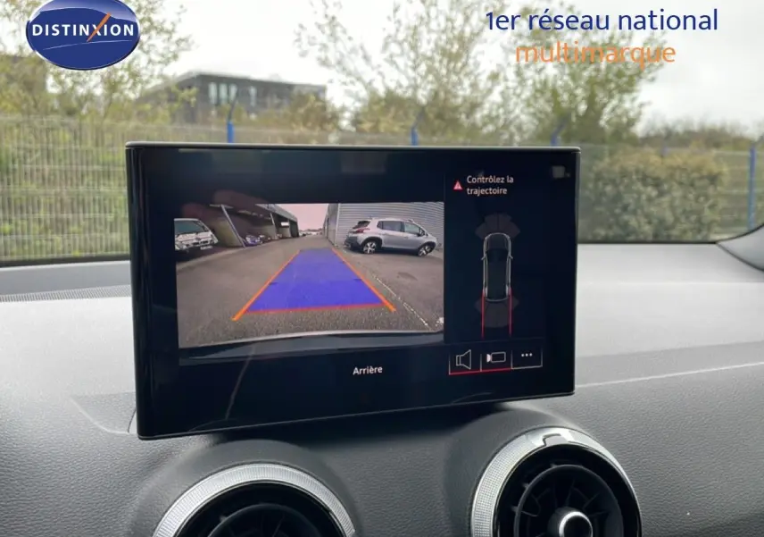 Écran central montrant la caméra de recul de l'Audi Q2 noire, avec guidage de trajectoire visible.