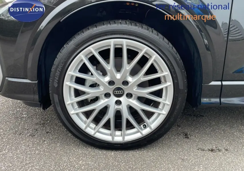 Gros plan sur la roue avant gauche de l'Audi Q2 noir mito metal avec jante alliage multibranches argentée.