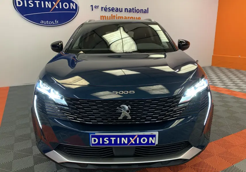 Vue avant d'un Peugeot 5008 bleu Célèbes avec phares LED allumés dans un showroom lumineux.