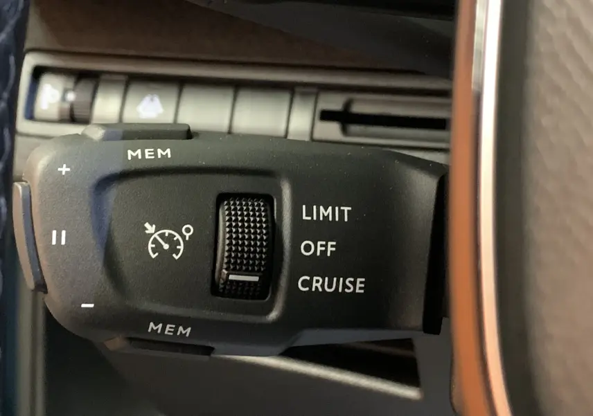 Gros plan sur la commande de régulateur de vitesse au volant d’un Peugeot 5008 bleu, intérieur noir.