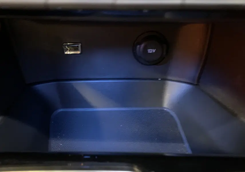 Détail de la prise 12V et port USB dans le rangement intérieur du Peugeot 5008 Bleu Célèbes 2024.