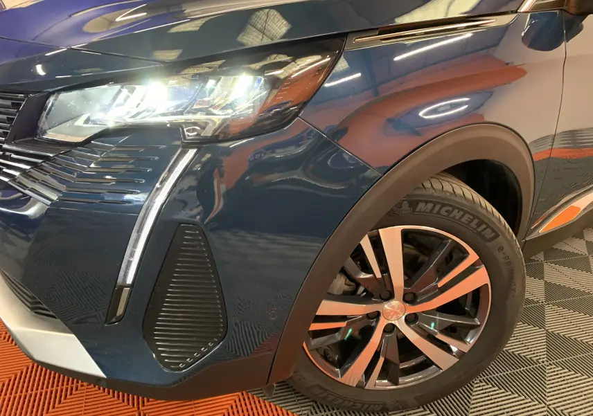 Gros plan sur l'avant droit bleu Célèbes du Peugeot 5008 2024, avec phare allumé et jante alliage bicolore.