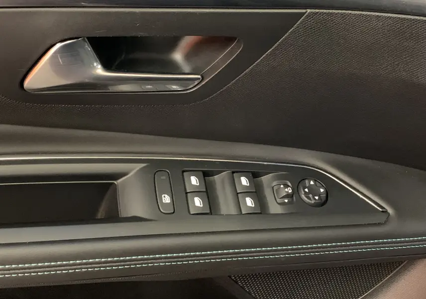 Gros plan sur la commande des vitres et rétroviseurs côté conducteur du Peugeot 5008 bleu, avec surpiqûres bleues visibles.