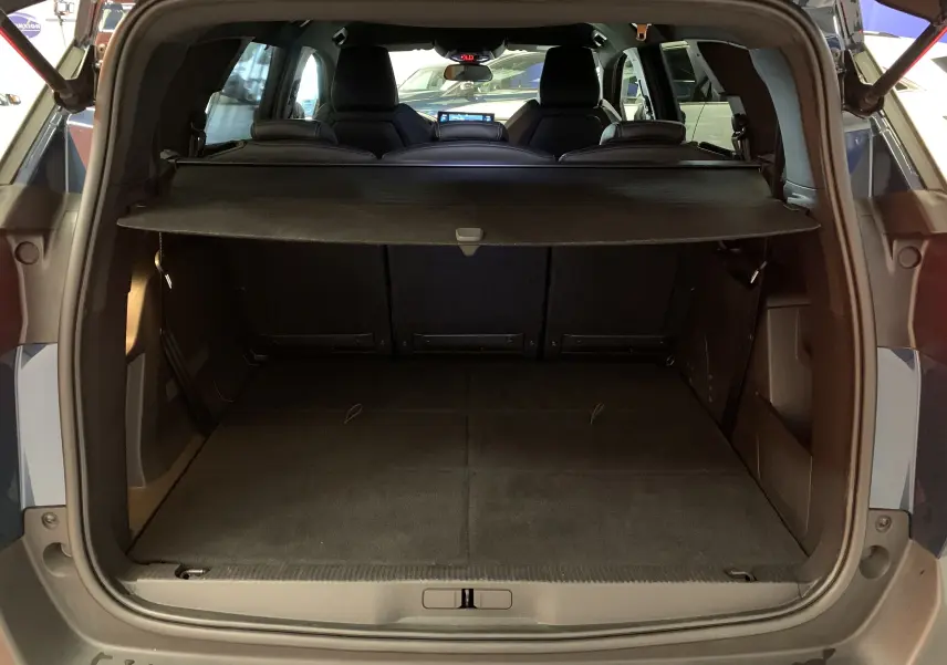 Vue arrière du coffre ouvert du Peugeot 5008 Bleu Célèbes, montrant l'espace de chargement et la tablette cache-bagages.