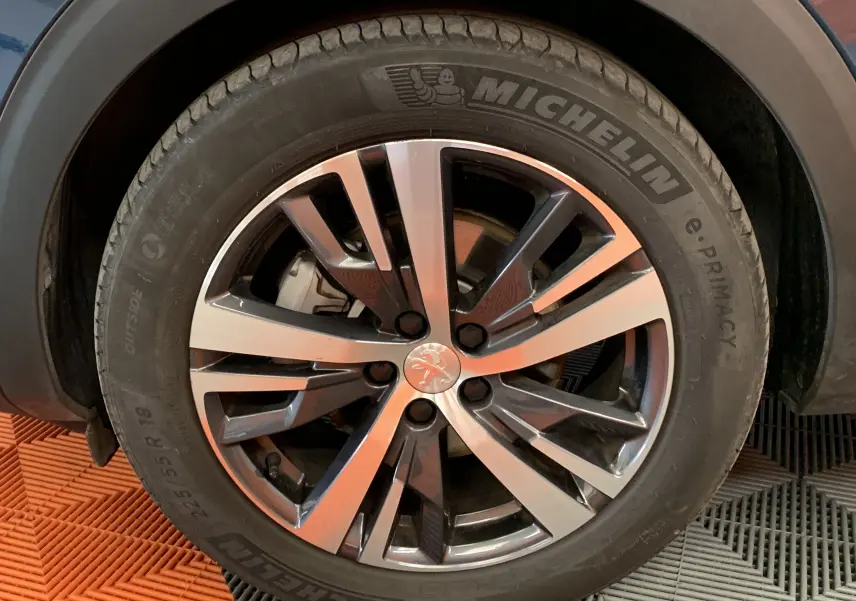 Gros plan sur la roue avant gauche du Peugeot 5008 Bleu Célèbes avec jante alliage bicolore et pneu Michelin.