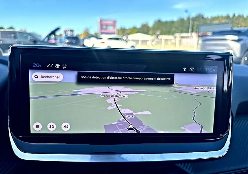 Écran tactile central du tableau de bord de la Peugeot 208 noir, affichant la navigation GPS en extérieur.
