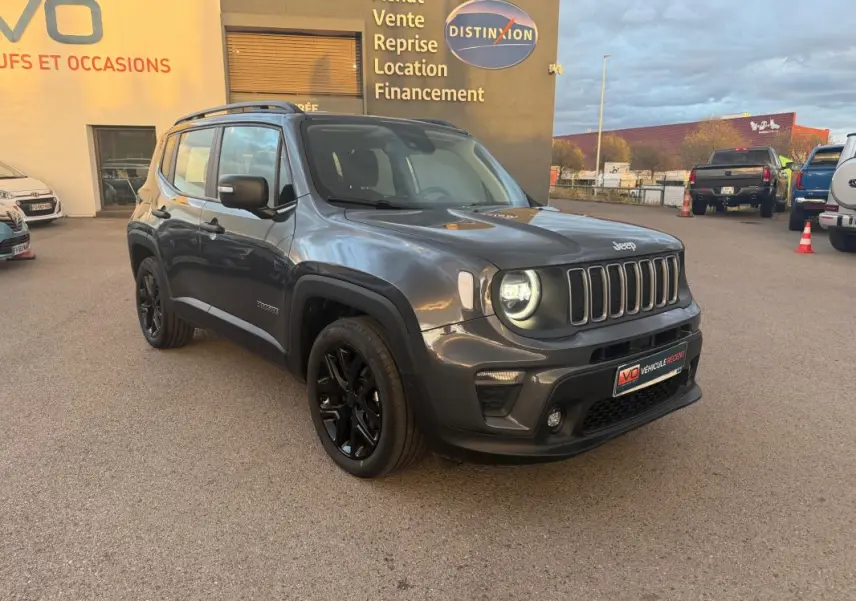 Jeep Renegade gris anthracite en 3/4 avant droit avec jantes alliage noires et barres de toit visibles.
