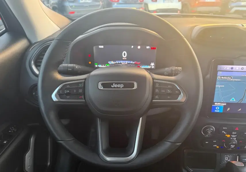 Vue intérieure centrée sur le volant Jeep noir avec tableau de bord numérique et écran tactile de navigation.
