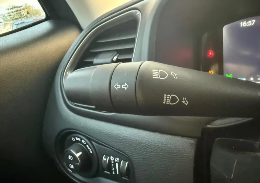 Gros plan sur la commande des phares et clignotants du Jeep Renegade gris anthracite, tableau de bord partiellement visible.