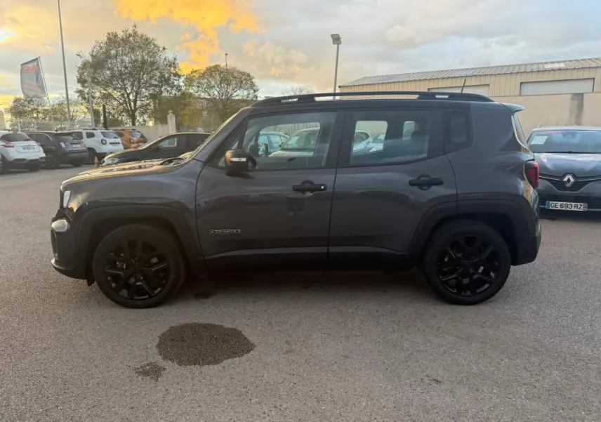 Jeep Renegade gris anthracite vue de profil côté gauche, avec barres de toit et jantes alliage noires 18 pouces.