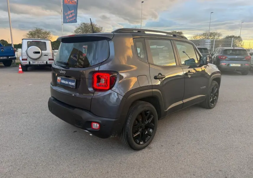 Jeep Renegade gris anthracite vu en 3/4 arrière droit, avec barres de toit et jantes alliage noires de 18 pouces.