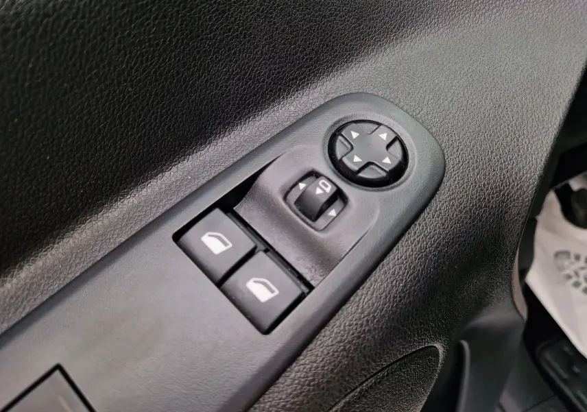 Gros plan sur les commandes de réglage des rétroviseurs et des vitres électriques côté conducteur du Citroën Berlingo blanc de 2021.