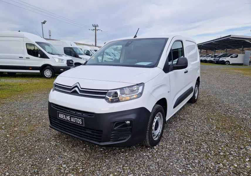 Vue 3/4 avant d’un Citroën Berlingo blanc 2021 avec pare-chocs noir et jantes acier sur un parking extérieur.