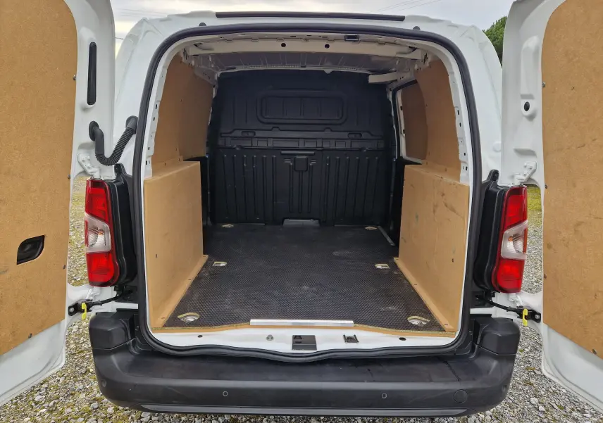 Vue arrière du Citroën Berlingo blanc 2021 avec portes ouvertes montrant l’espace de chargement protégé par des panneaux en bois.