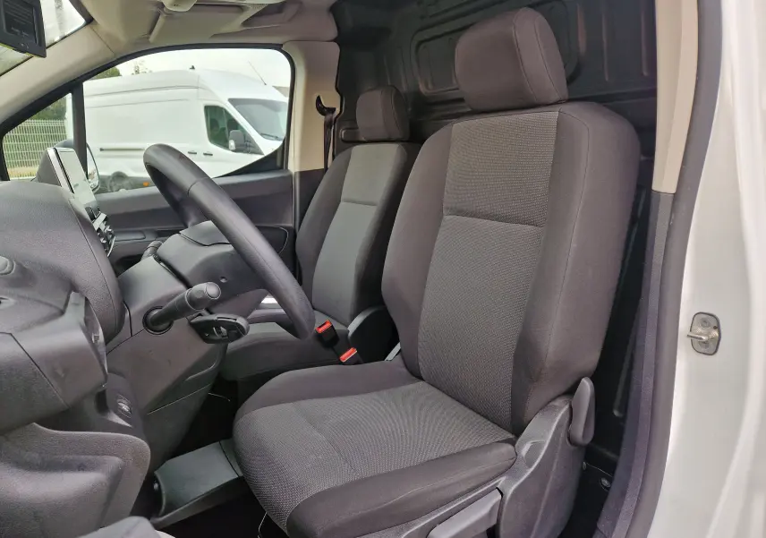 Vue intérieure côté conducteur du Citroën Berlingo blanc 2021, montrant les sièges tissu gris et le volant.