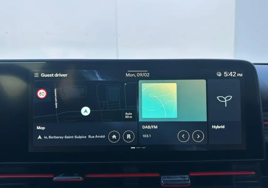 Vue plongeante sur la console centrale noire du Hyundai Kona 2026 avec porte-gobelets et commandes Drive Mode.