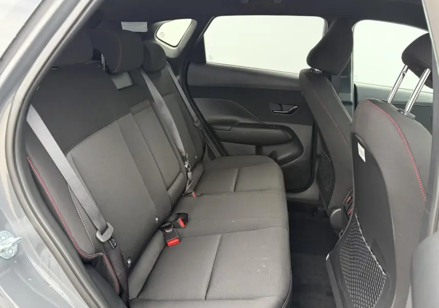 Vue intérieure côté gauche sur la banquette arrière noire avec surpiqûres rouges du Hyundai Kona 2026 gris métallisé.