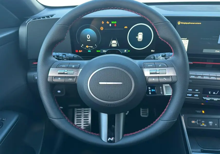 Vue 3/4 arrière droite du Hyundai KONA II hybride en gris métallisé Ecotronic, avec feux arrière LED et double sortie d'échappement.