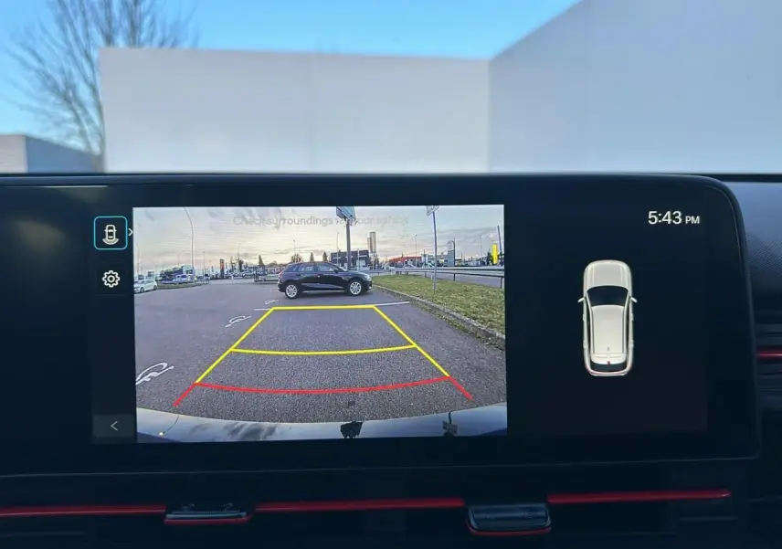 Vue écran multimédia montrant la caméra de recul du Hyundai Kona gris Ecotronic en stationnement, avec lignes de guidage colorées.