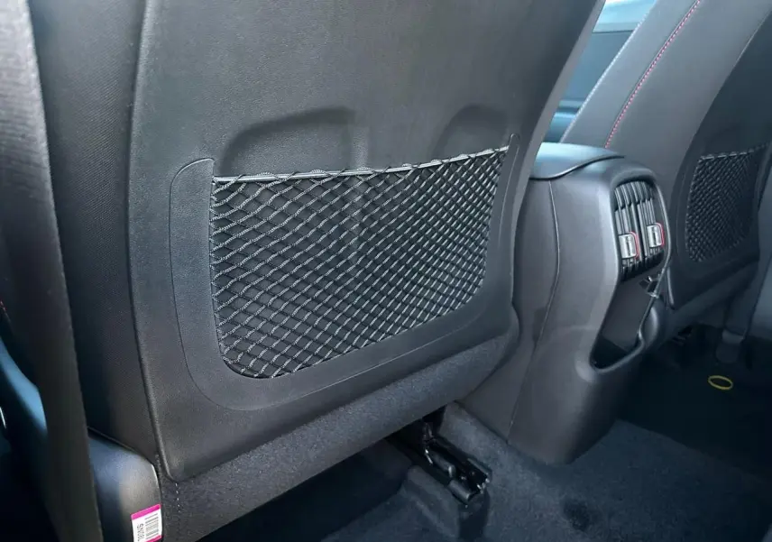 Détail de l’arrière des sièges avant noirs avec filet de rangement et prises d’aération au centre du Hyundai Kona 2026.