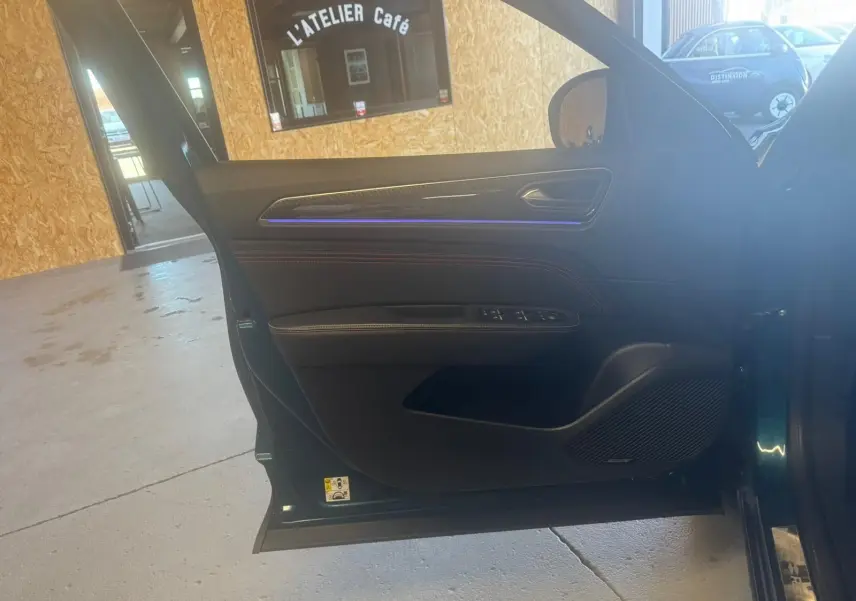 Vue intérieure de la porte avant gauche ouverte d’un Renault Arkana bleu, avec commandes électriques et éclairage d’ambiance bleu.