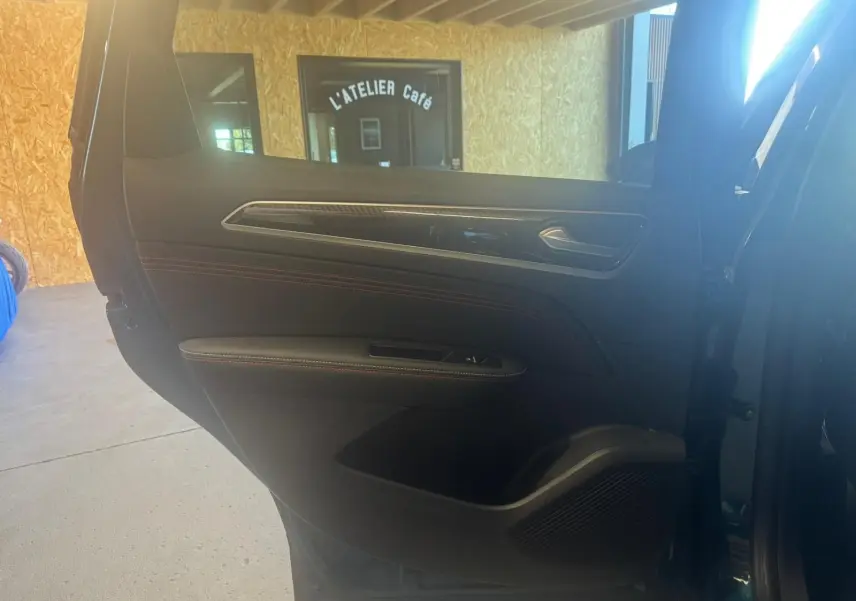 Vue intérieure de la porte arrière droite du Renault Arkana bleu, avec garniture noire et surpiqûres rouges visibles.