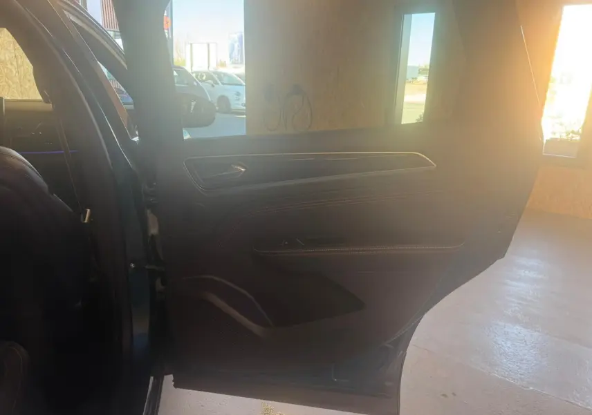 Vue intérieure de la porte arrière gauche d'un Renault Arkana bleu, avec détails en cuir noir et surpiqûres rouges.