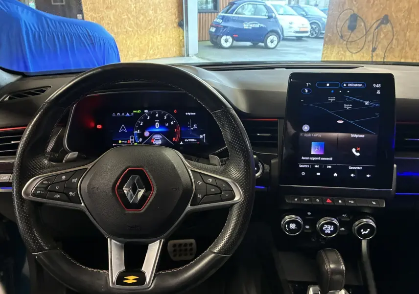 Vue intérieure du poste de conduite du Renault Arkana bleu, avec volant multifonction, écran digital et console tactile centrale.