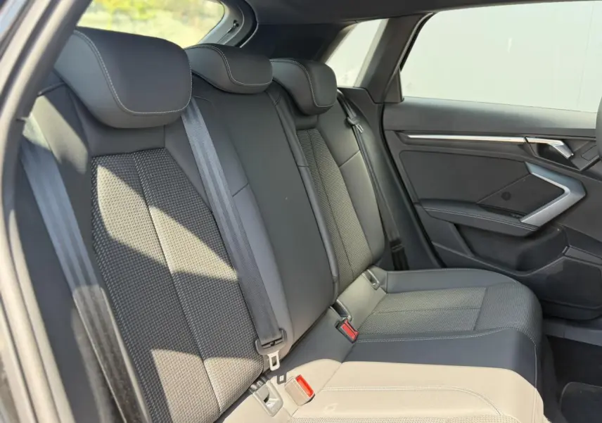 Vue latérale droite de la banquette arrière noire de l'Audi A3 Sportback 2025 avec ceinture et garnitures en tissu et cuir.