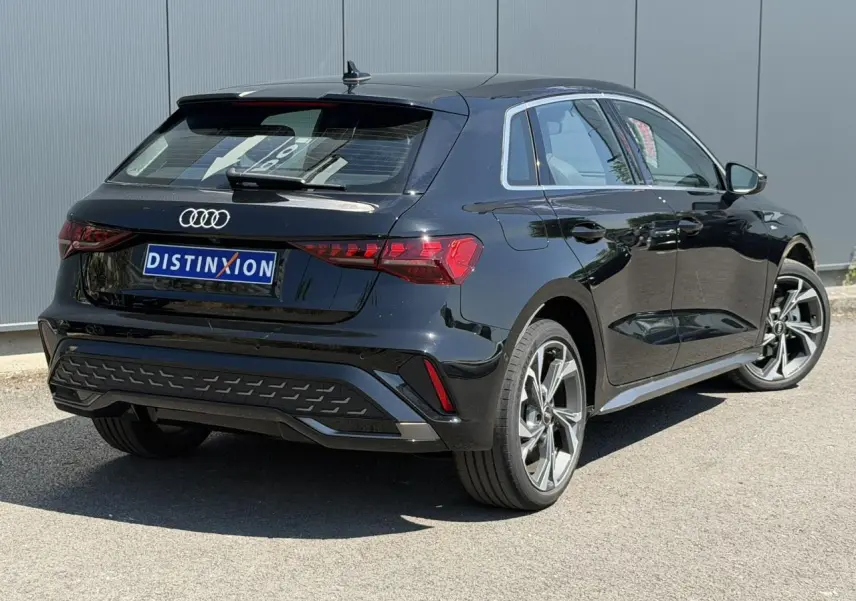 Audi A3 Sportback noir Mythe vue 3/4 arrière droit, avec jantes alliage 5 branches en Y et feux LED distinctifs.