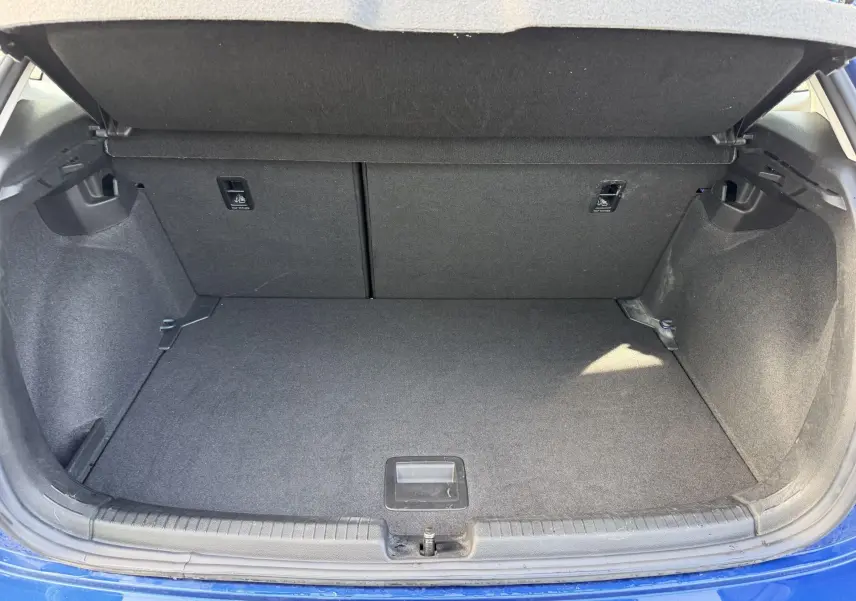 Coffre ouvert vu de l'arrière d'une Volkswagen Polo bleue, montrant un espace de chargement propre et spacieux.
