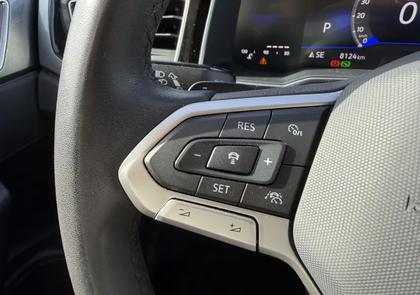 Gros plan sur le volant cuir multifonctions côté gauche de la Volkswagen Polo bleue avec commandes de régulateur adaptatif.