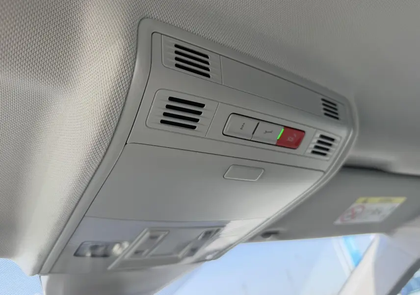 Vue intérieure en plongée du plafonnier gris clair avec boutons SOS et ventilation dans une Volkswagen Polo bleue.