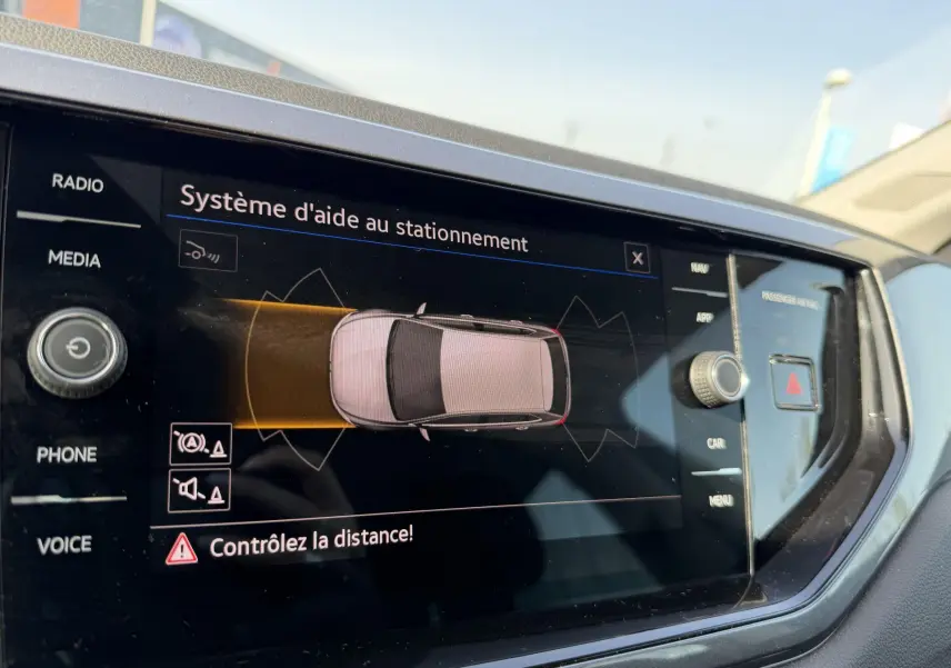 Écran tactile intérieur montrant le système d'aide au stationnement de la Volkswagen Polo bleue, vue de près côté conducteur.