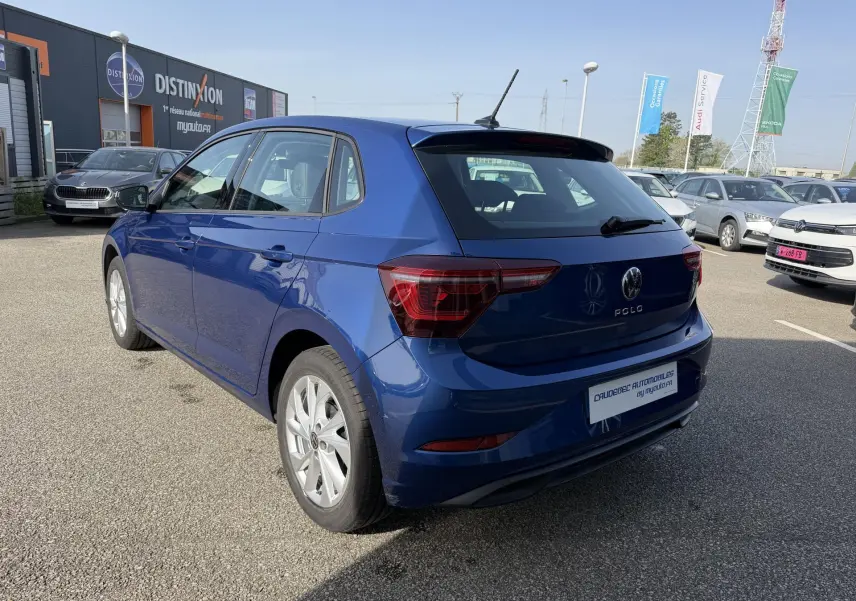Vue 3/4 arrière droite d'une Volkswagen Polo bleue métallisée avec jantes alliage et feux arrière LED, stationnée en extérieur.