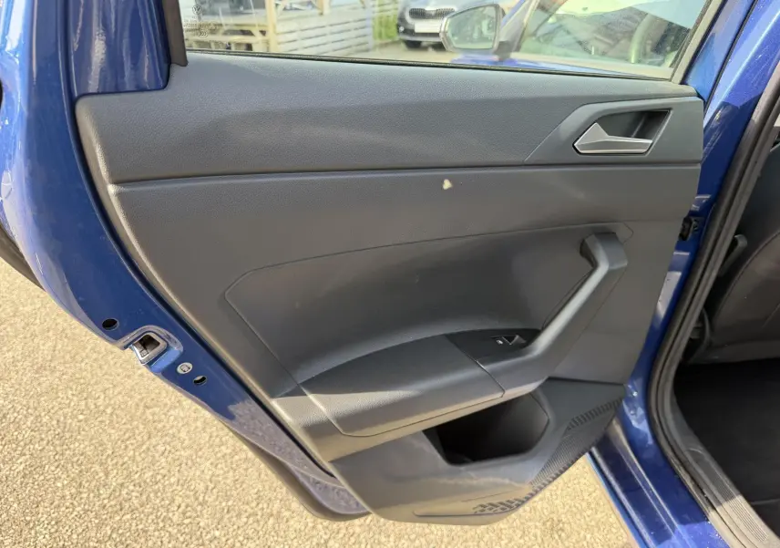 Vue rapprochée de la porte arrière gauche bleu récif métallisé d'une Volkswagen Polo 2025 avec panneau intérieur noir.