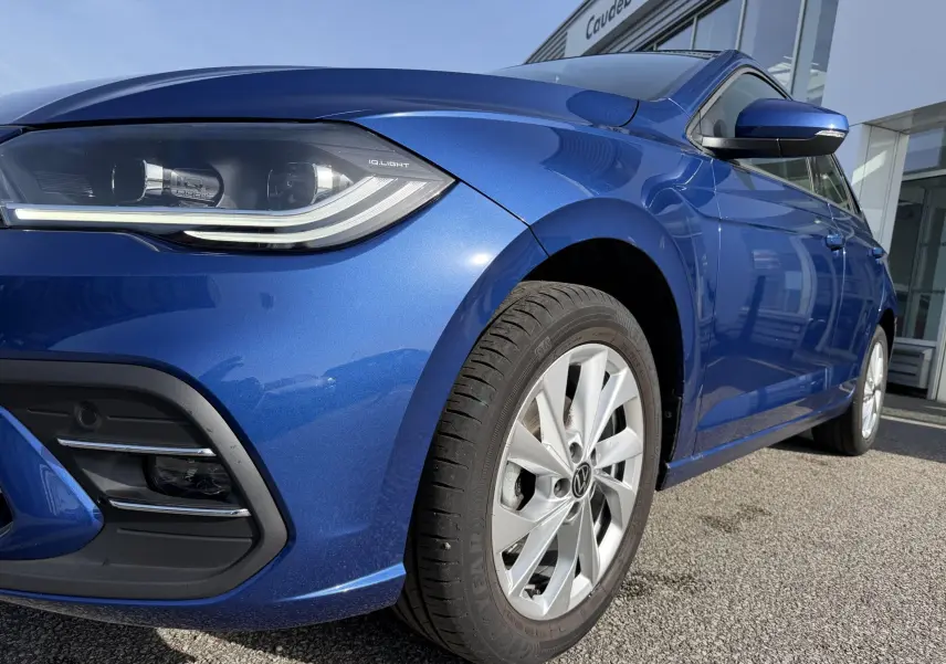 Vue 3/4 avant droit d'une Volkswagen Polo bleue métallisée avec phares IQ.Light et jantes alliage 16 pouces.