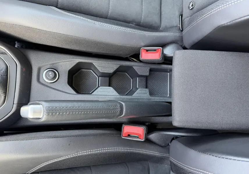 Vue plongeante sur la console centrale noire de la Volkswagen Polo avec frein à main manuel et sièges tissu gris.