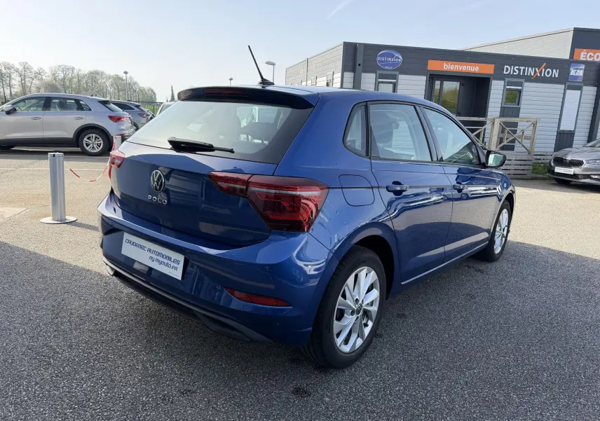 Vue 3/4 arrière droite d'une Volkswagen Polo bleu récif métallisé avec jantes alliage 16 pouces sur parking extérieur.