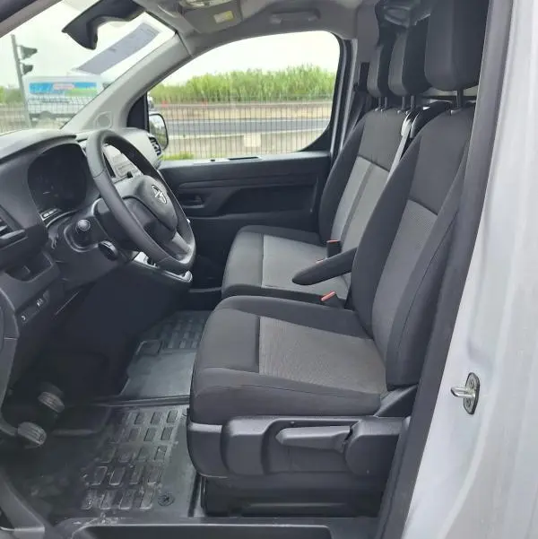 Vue intérieure côté conducteur de l'Opel Vivaro blanc 2025, montrant les sièges avant et le volant réglable.